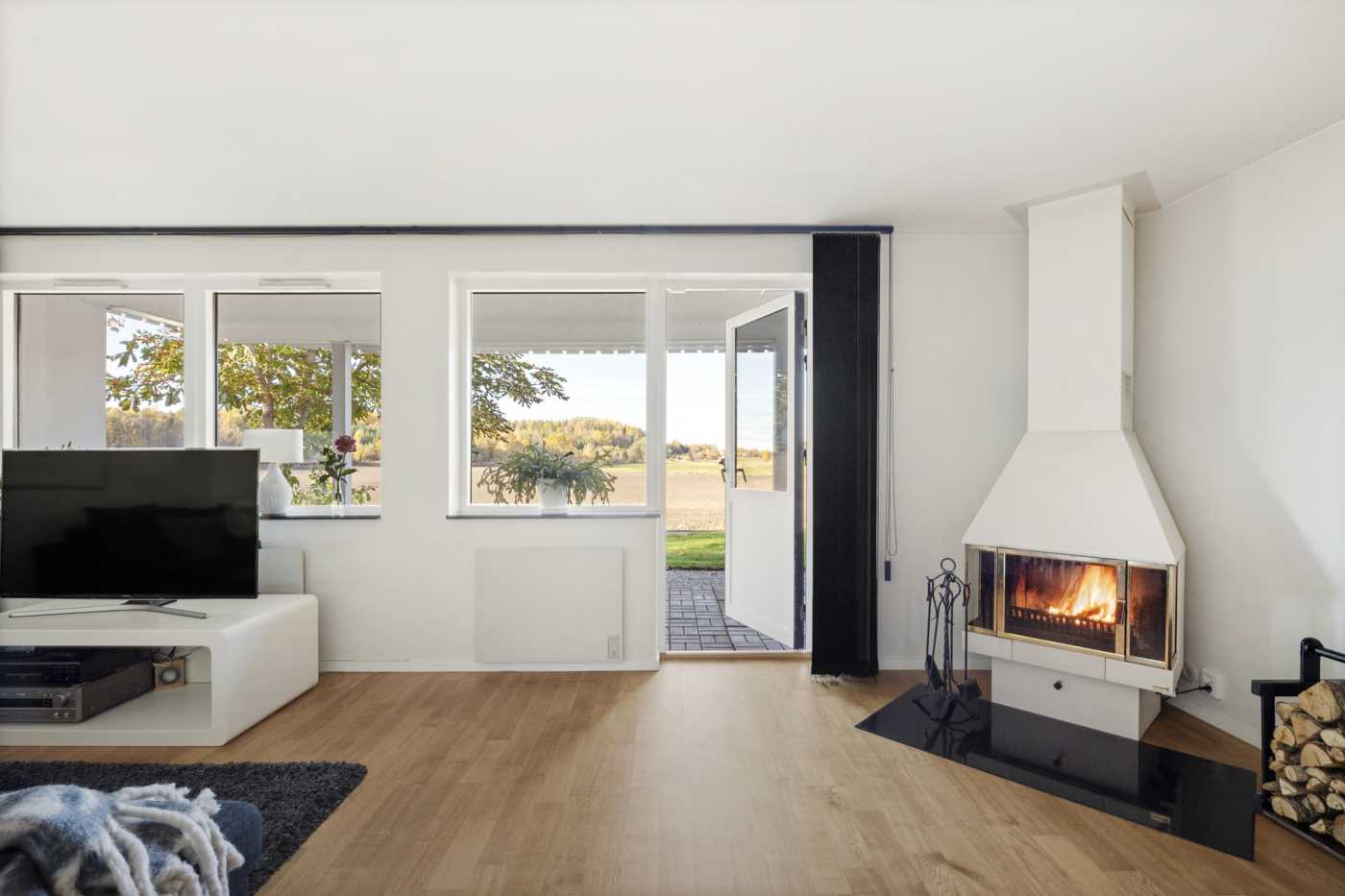 Fönsterparti med vacker vy och utgång till stenlagd uteplats delvis under tak